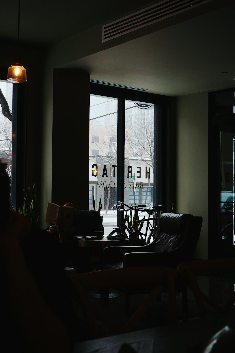 Persona che legge su una poltrona in un caffè con la neve fuori.
